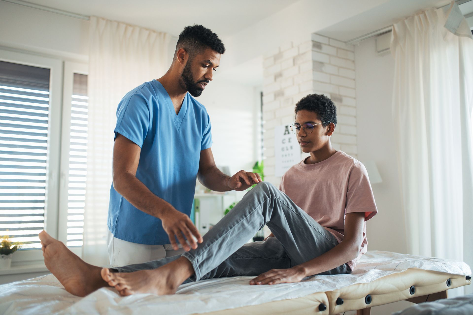 Therapist helping patient with leg exercises on treatment table.