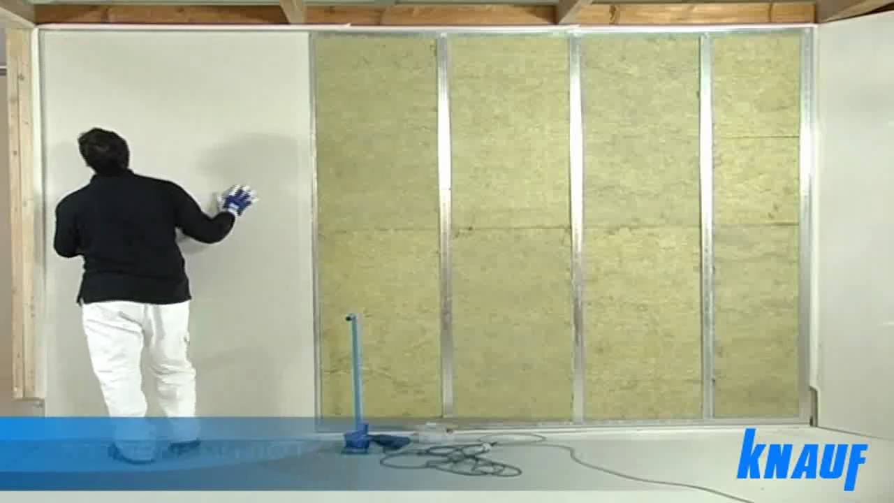 Un uomo è in piedi davanti a un muro con la scritta knauf.