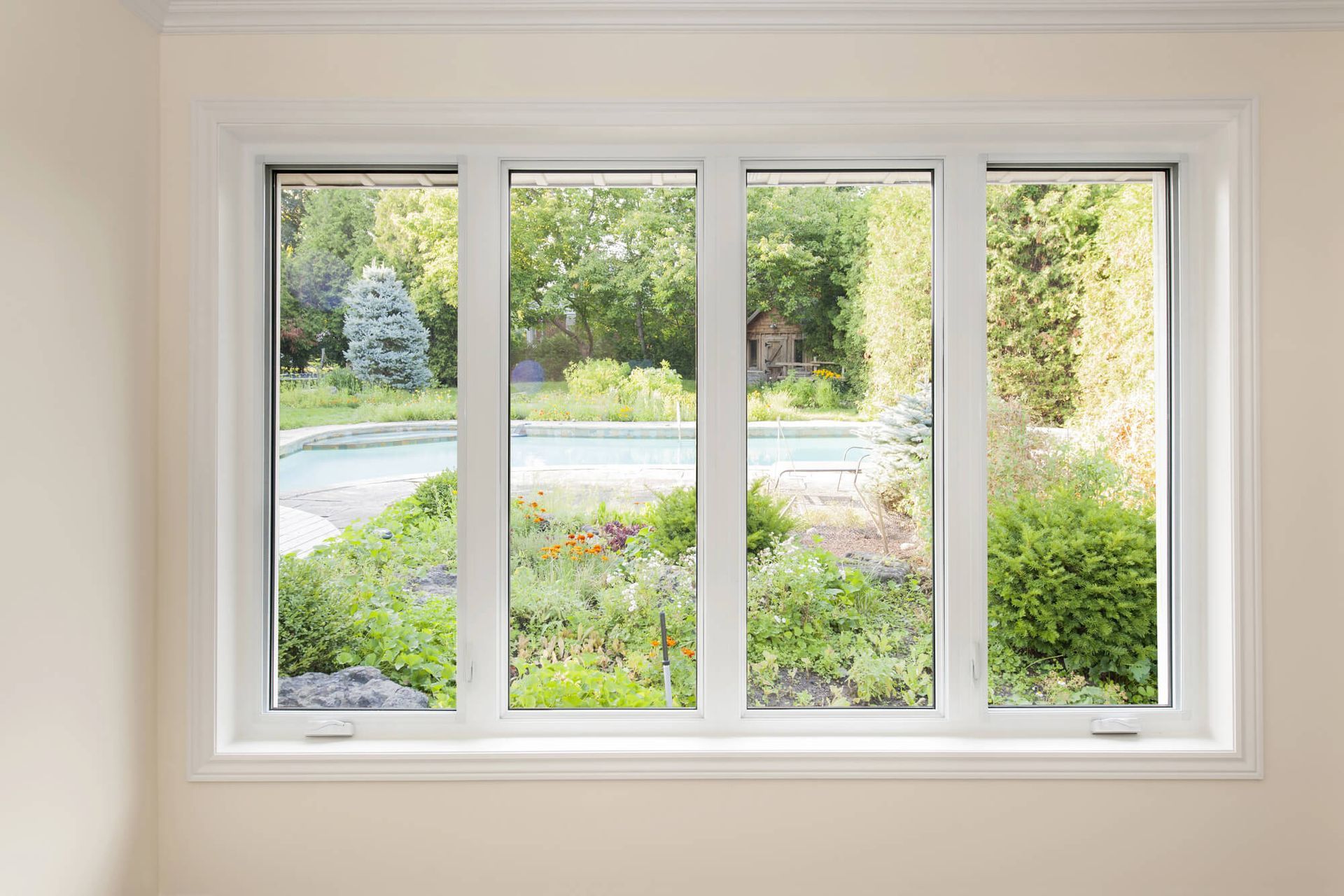 White-framed window overlooking a green garden and driveway on a sunny day