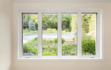 White-framed window overlooking a green garden and driveway