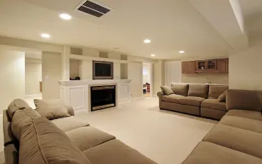 Spacious beige living room with sectional sofas, fireplace, wall-mounted TV, and recessed lighting