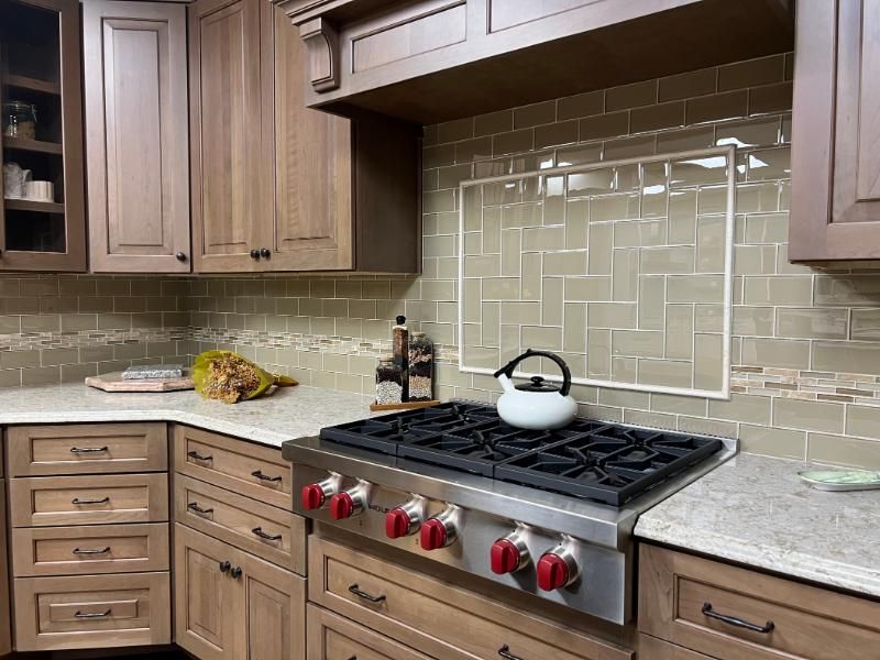 Modern kitchen with wood cabinets, beige tile backsplash, granite counters, and a gas stove with a kettle.