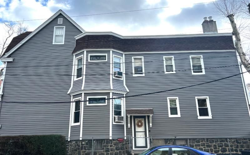 Gray two-story house with white trim and a small front bay window.