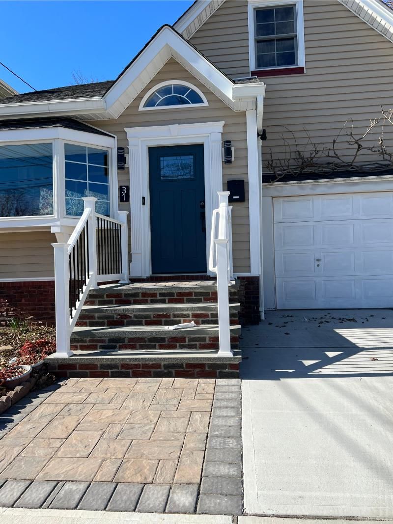 Front entrance of a house with blue door, white trim, brick steps, and an attached garage.
