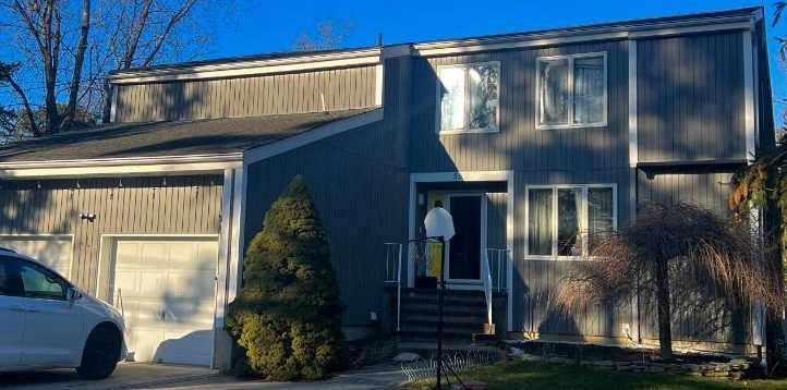 Two-story house with attached garage, front porch, and car parked in the driveway in daylight