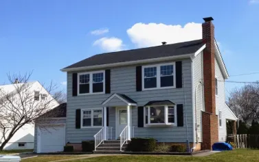 Two-story gray house with white trim and a front porch under a blue sky