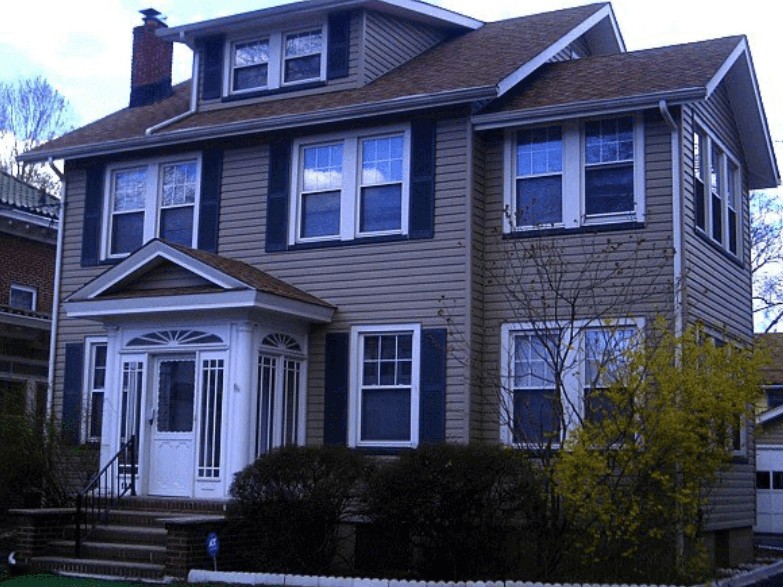 Two-story gray house with white trim and a front porch, seen from the street