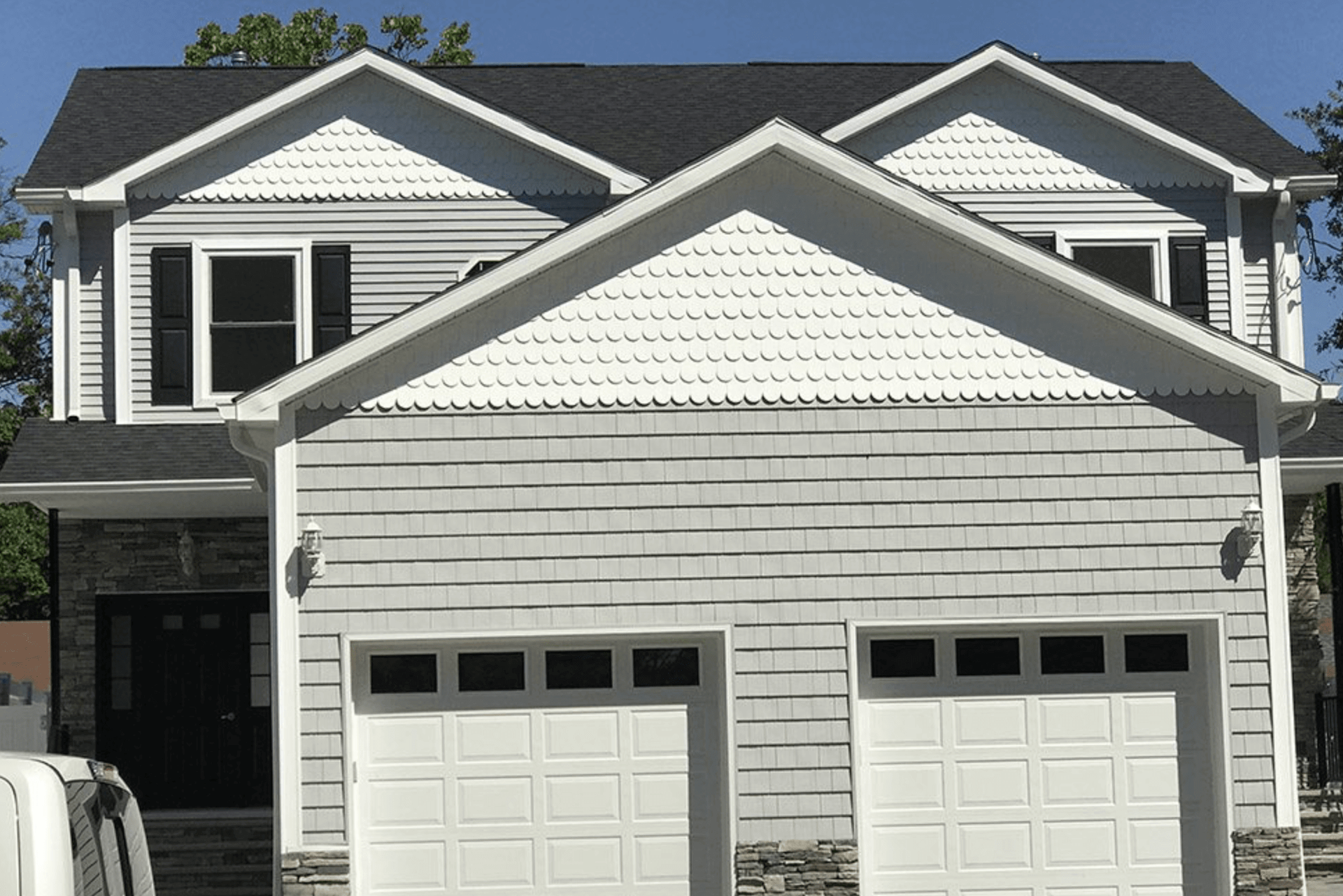 Suburban two-story house with white siding and a double garage under a dark roof