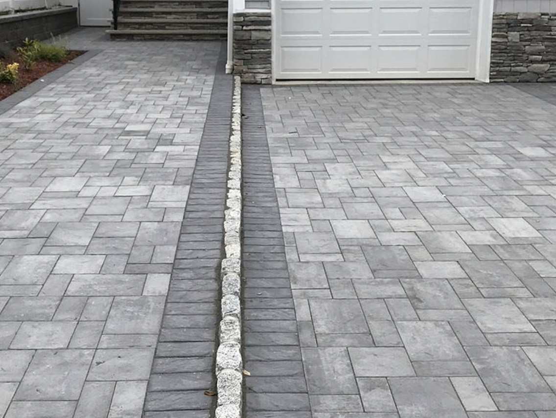 Stone driveway with a narrow drainage channel running down the center to a garage and steps.