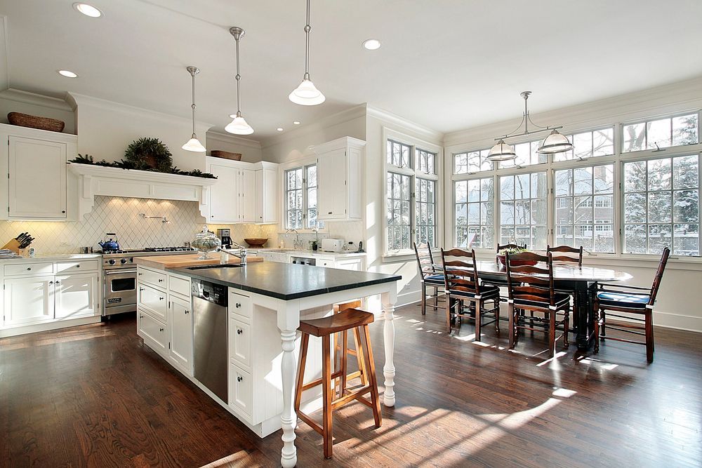 Open-concept kitchen and dining area with white cabinets, island, and sunlit hardwood floors