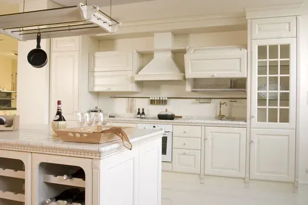 Bright white kitchen with island, cabinets, stove, and a glass-pane pantry door