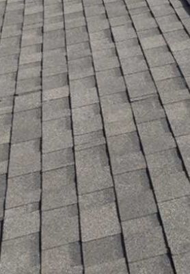 Gray shingled roof with overlapping rectangular asphalt tiles arranged in rows