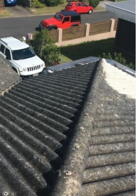 View from a tiled roof over a suburban street with two red trucks and a white SUV parked below.