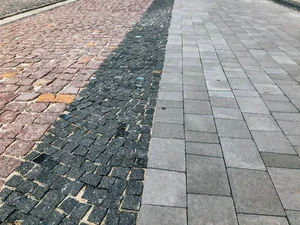 Brick walkway with a dark cobblestone stripe between pink and gray paving stones
