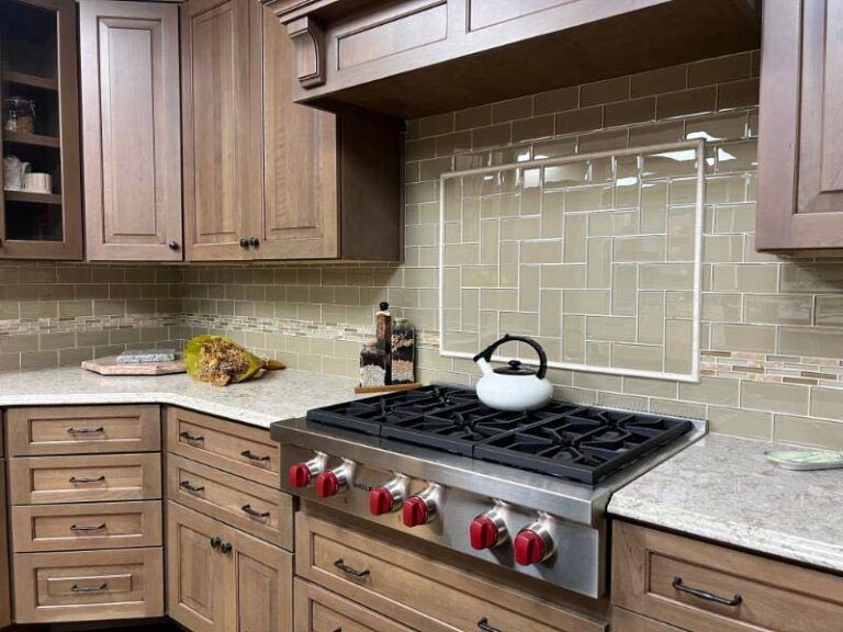 Modern kitchen with wood cabinets, beige tile backsplash, and a stainless range with a white kettle.