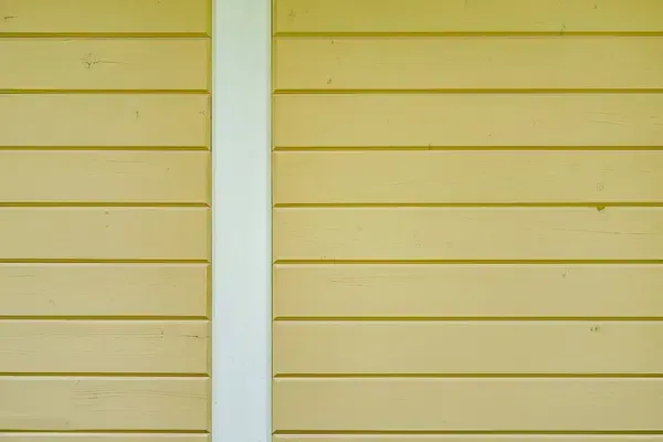 Yellow horizontal siding with a vertical white trim strip in the center