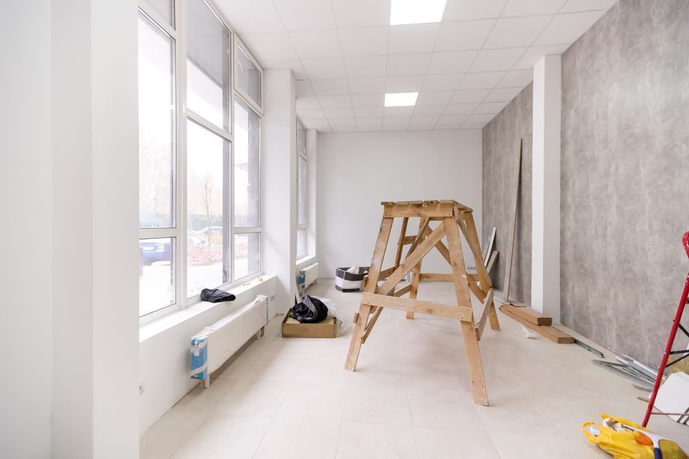 Bright hallway under renovation with ladders, tools, and exposed windows along one side