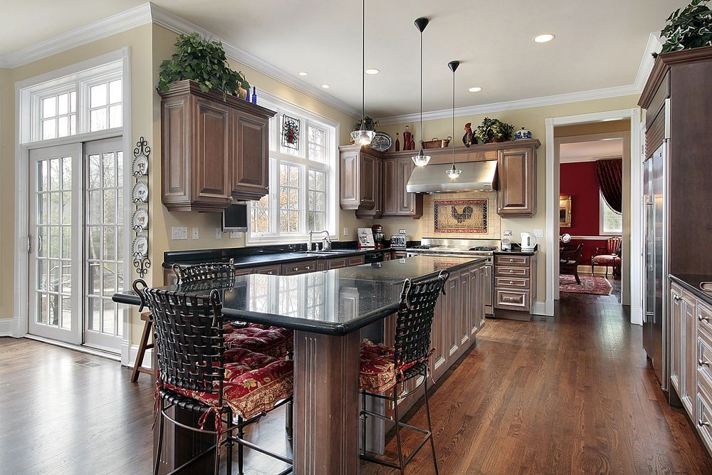 Bright kitchen with dark granite island, wood cabinets, large windows, and hardwood floors