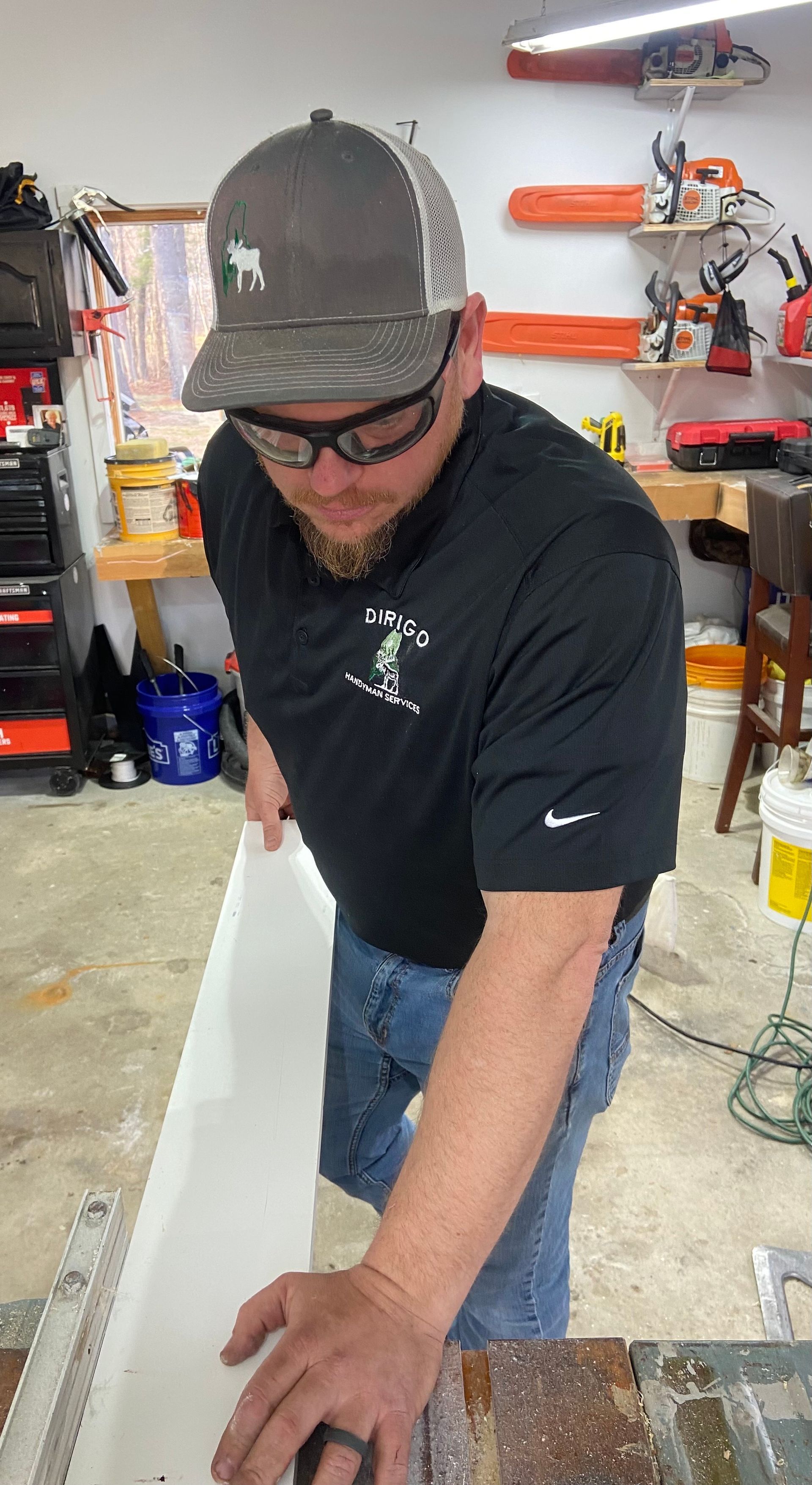 A man is cutting a piece of wood with a saw in a garage.