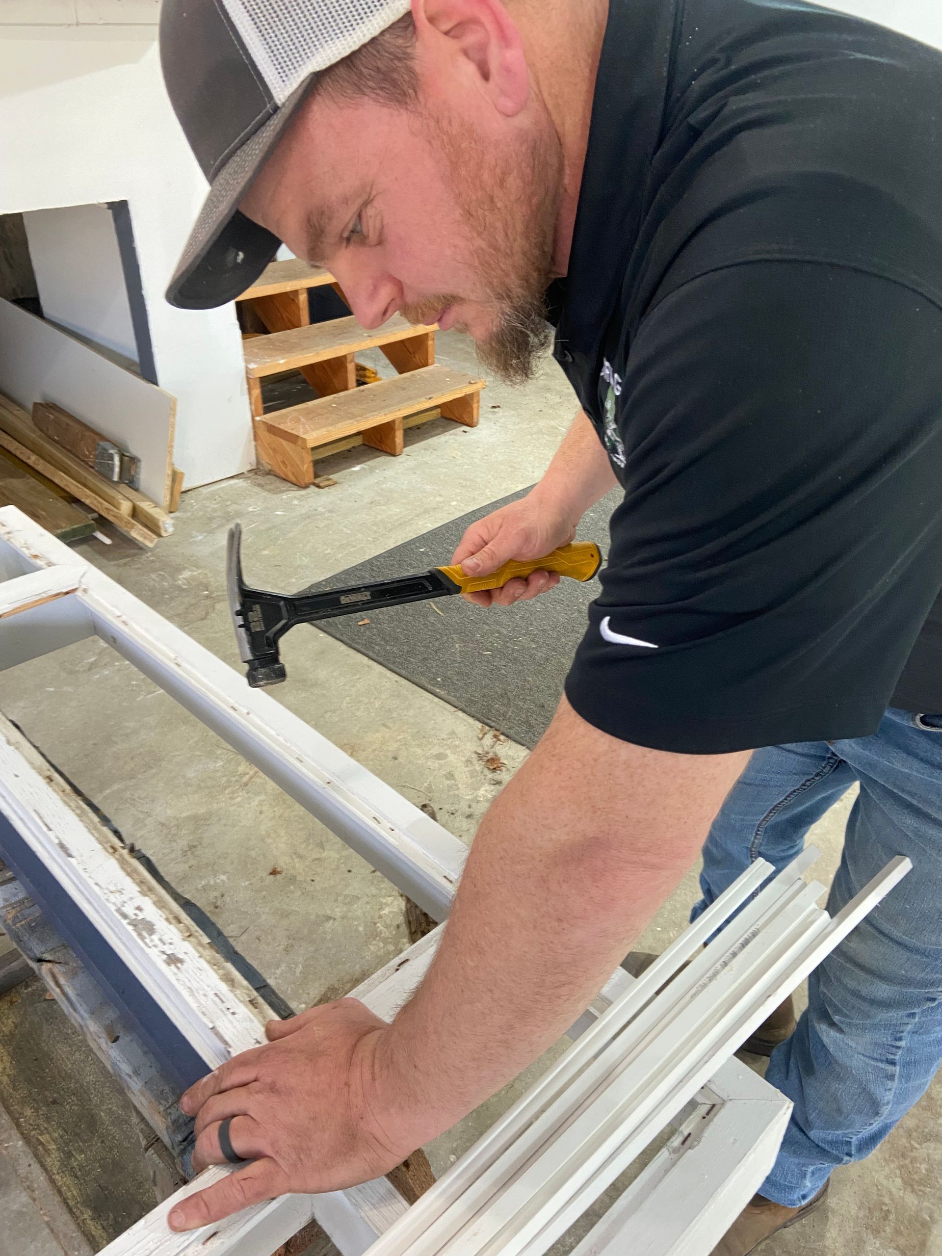 A man is using a hammer to fix a window frame.