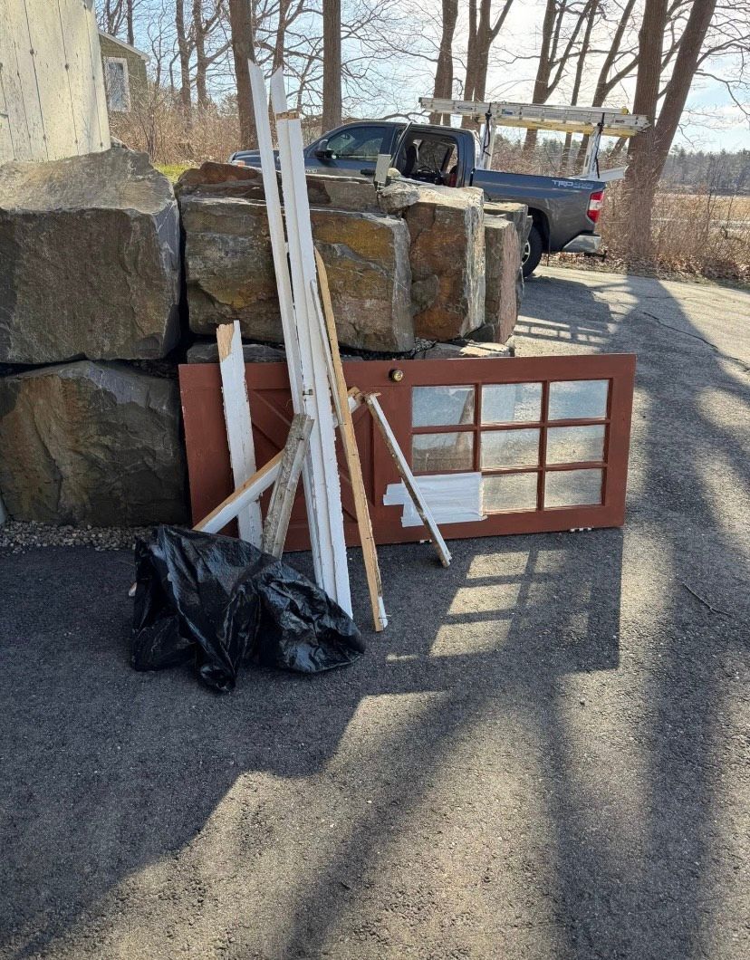 A pile of junk is sitting on the side of the road next to a truck.