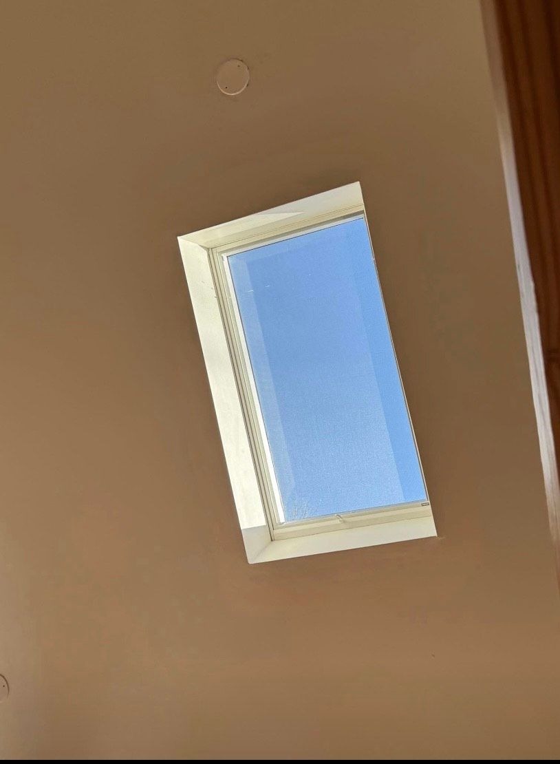 A skylight on the ceiling of a building with a blue sky behind it.