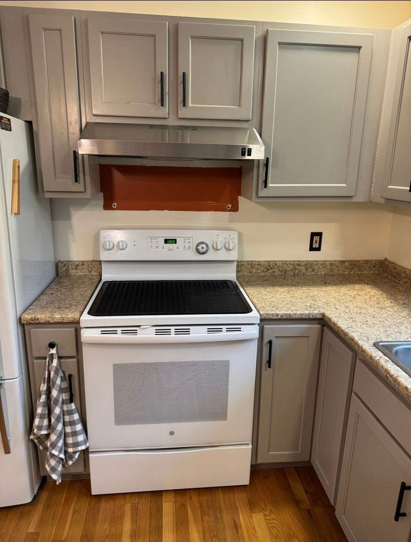 A kitchen with a stove , refrigerator , sink and cabinets.