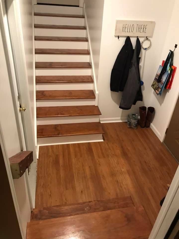A hallway with wooden floors and stairs in a house.