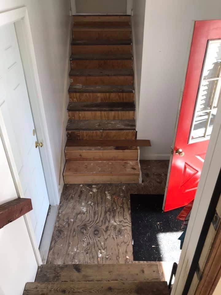 A wooden staircase in a house with a red door.