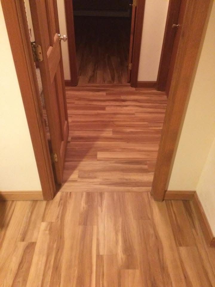 A hallway with hardwood floors and a doorway leading to a closet.