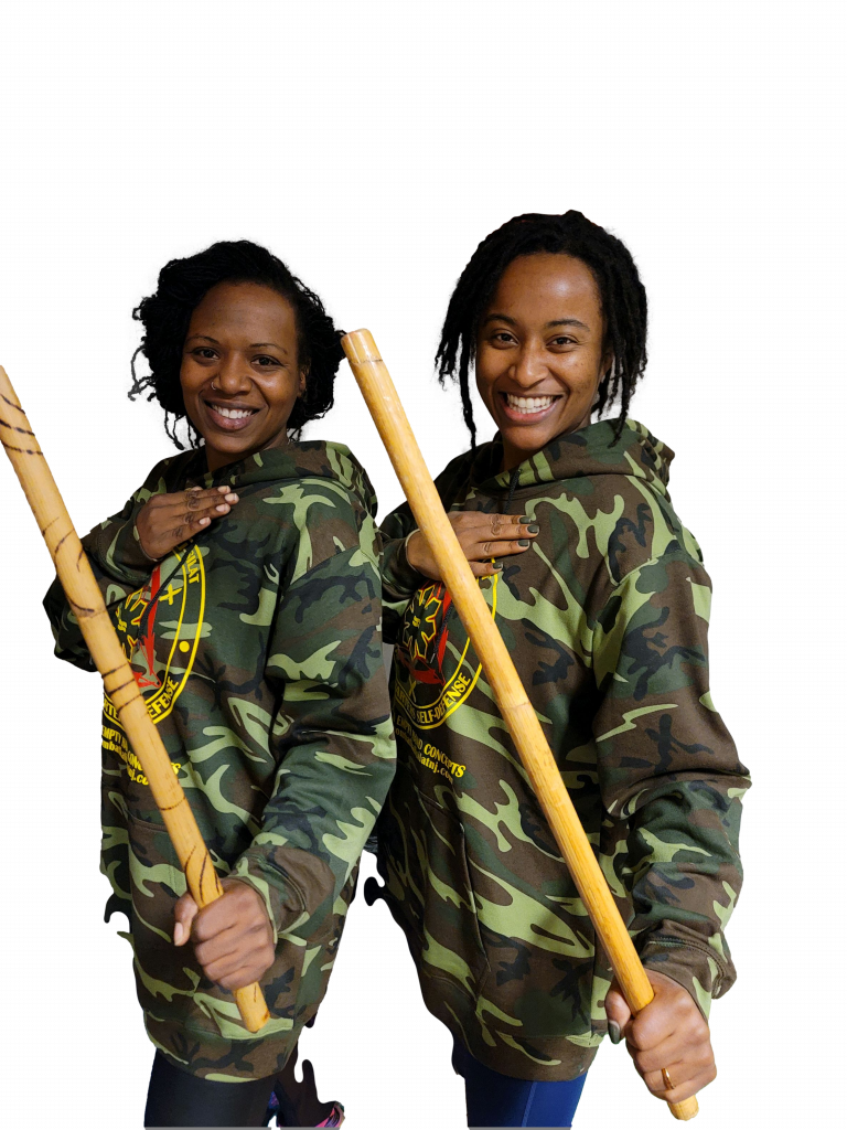 two women are standing next to each other holding wooden sticks .
