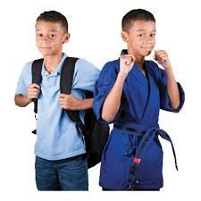 two young boys with backpacks and karate uniforms are standing next to each other .