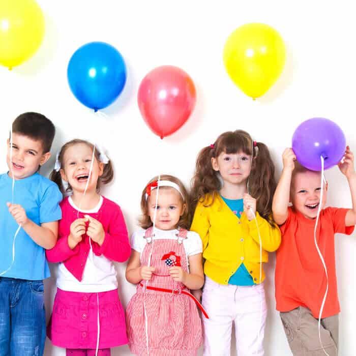 a group of children are standing next to each other holding balloons