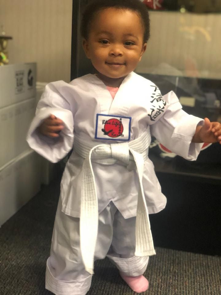 a little girl is wearing a white karate uniform