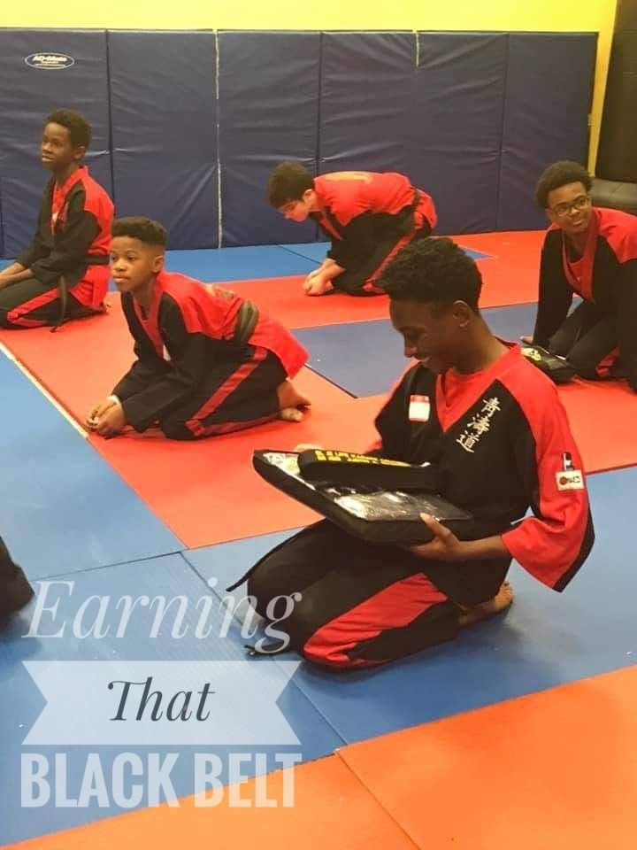 a group of young men are kneeling on a mat in a martial arts gym ..