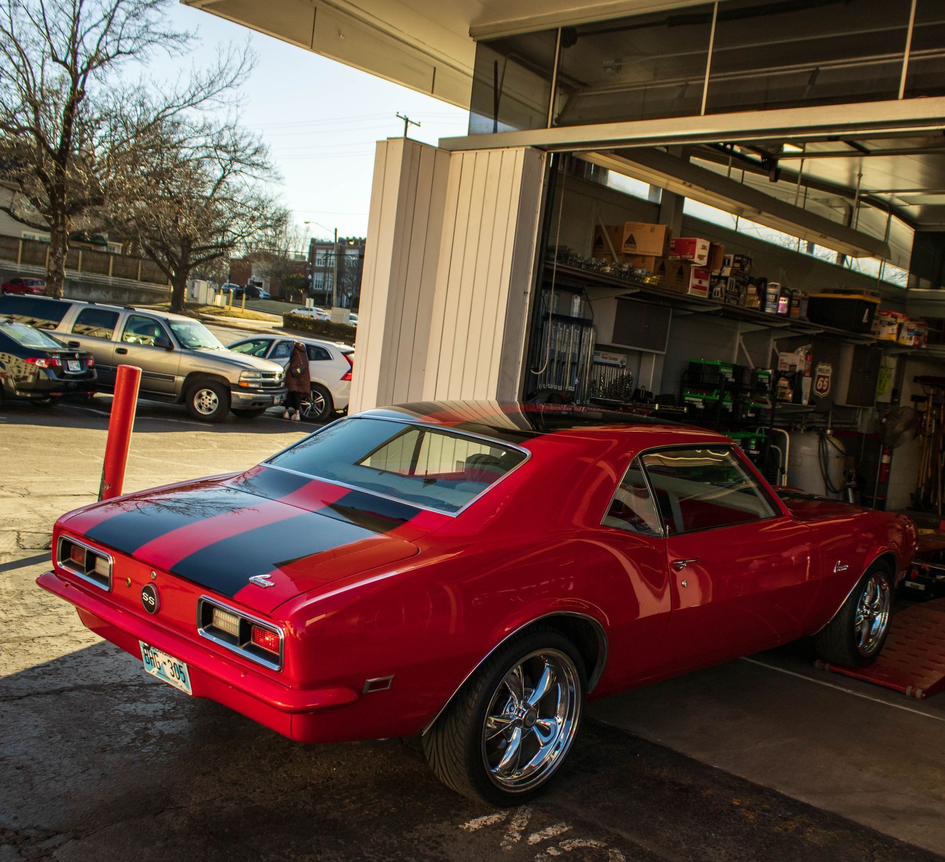 Red classic car with black stripes parked in a garage, sunlight, chrome wheels | Reeder's Auto & Tire Blog