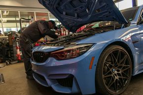 Technician Inspecting Blue BMW During Service | Reeder's Auto & Tire Blog