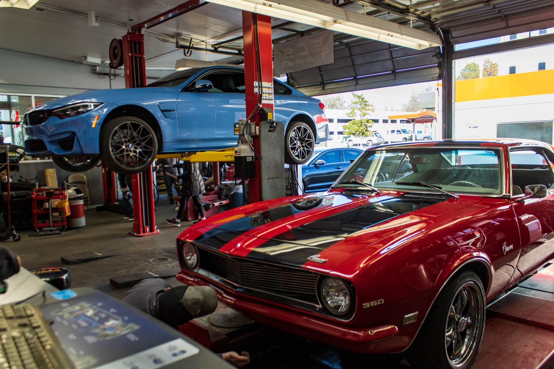 Classic Red Muscle Car And Blue BMW On Hydraulic Lifts | Reeder's Auto & Tire Blog