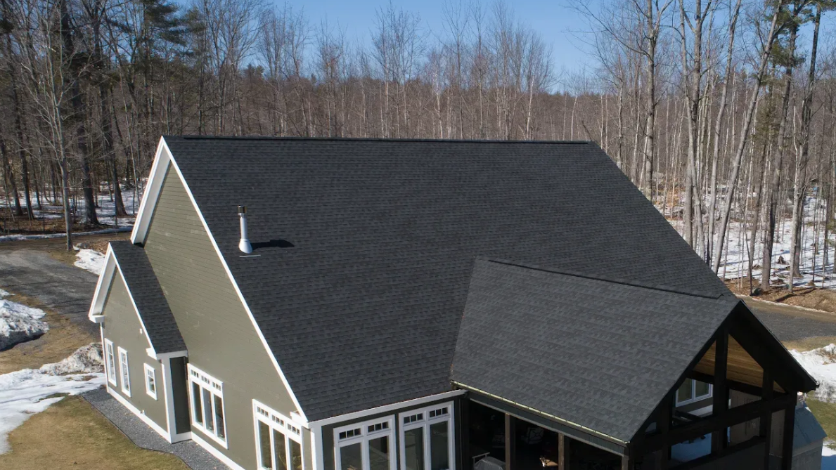 A kitchen with white cabinets, a black stove, and a window with a checkered curtain.