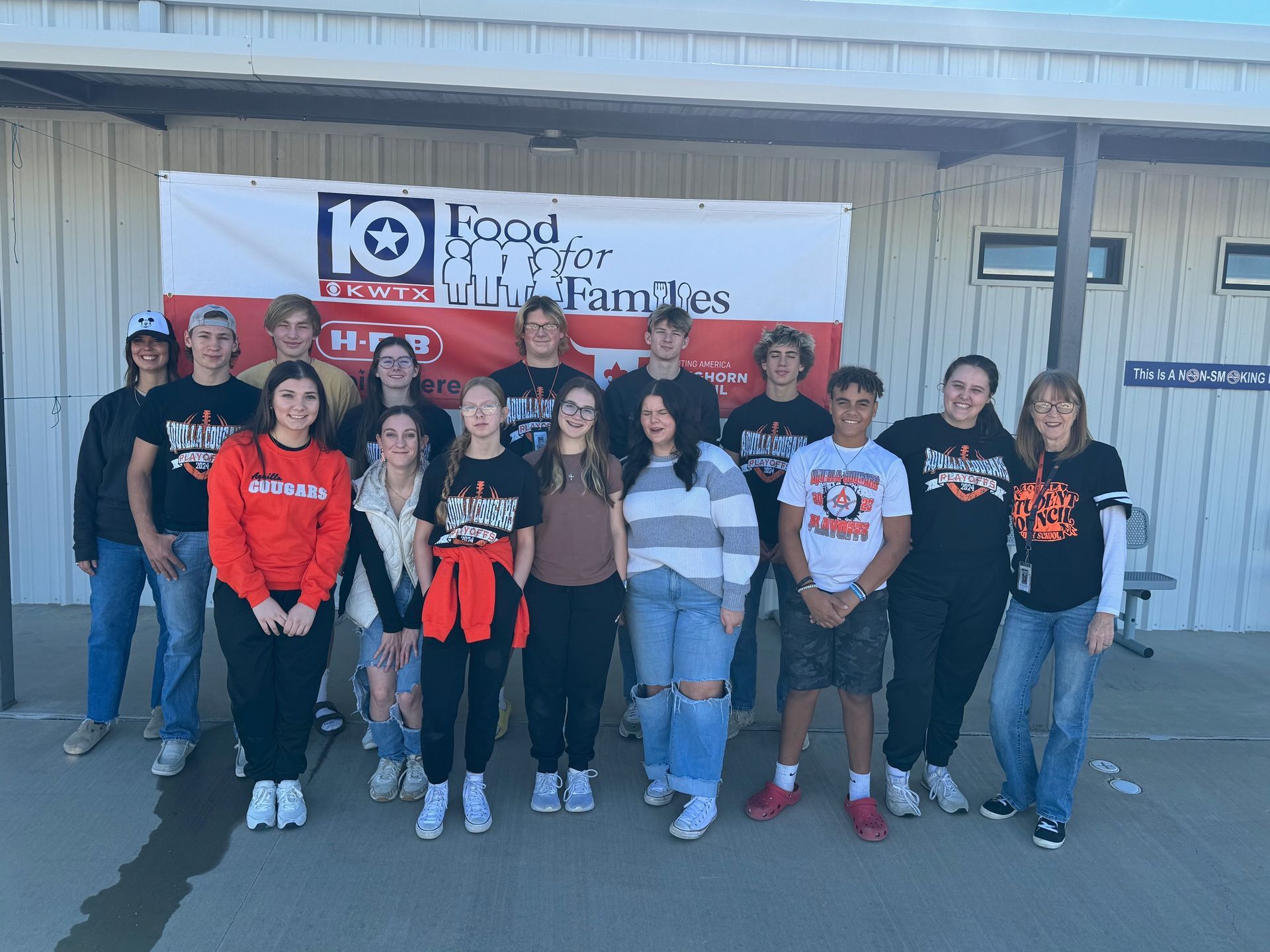 A group of people are standing in front of a sign that says food for families.