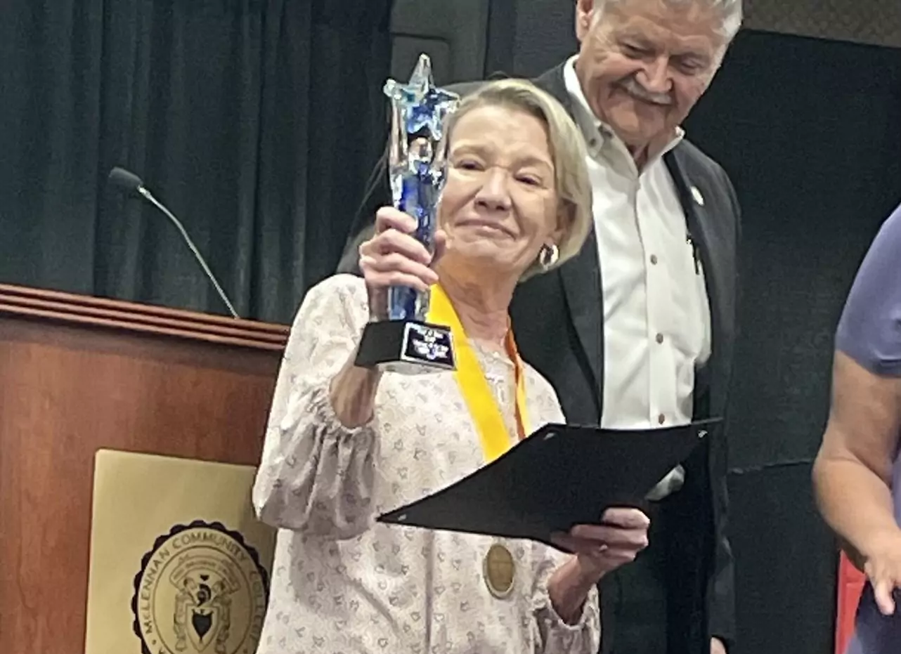 A woman is holding a trophy and a medal while standing next to a man.