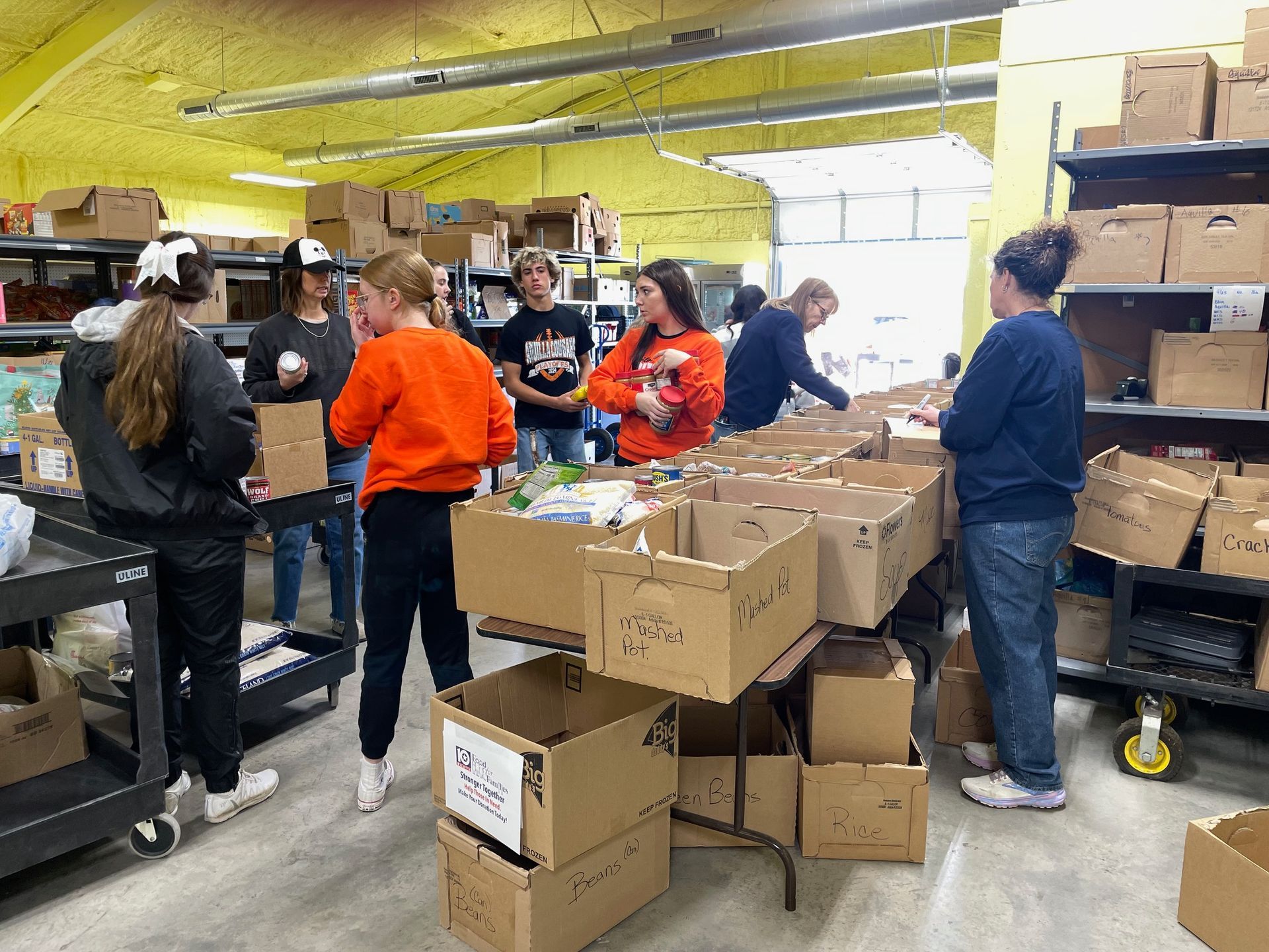 A group of people are working in a warehouse filled with lots of boxes.