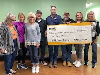 A group of people standing next to each other holding a large check.