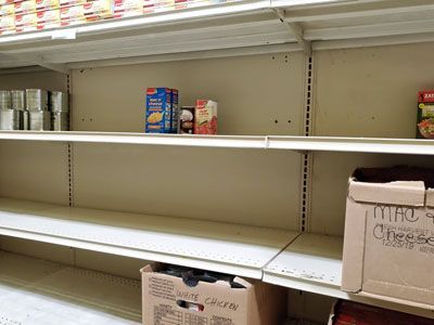 Empty shelves in a store with a box that says mac cheese on it