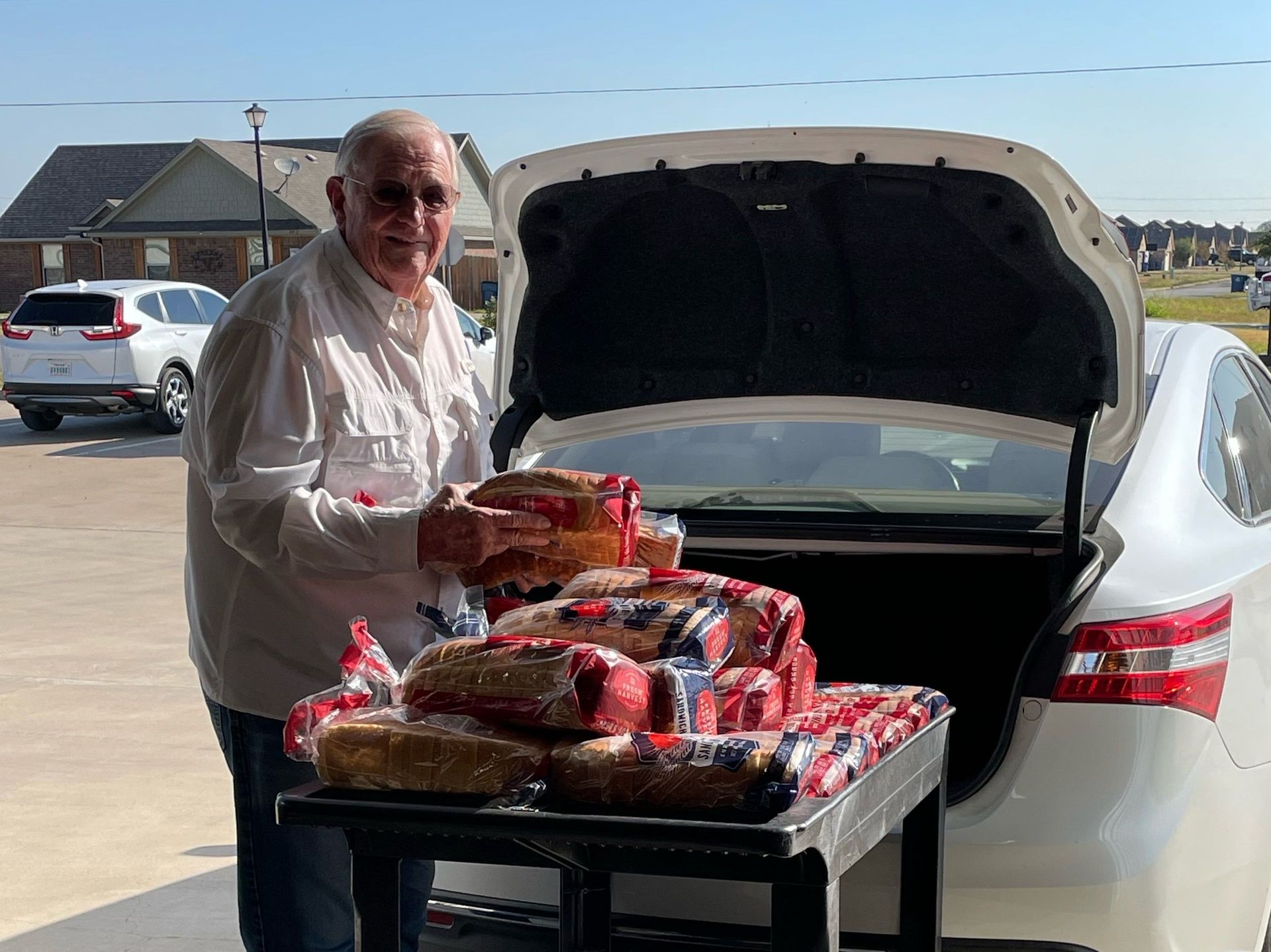 A man is loading food into the back of a car.