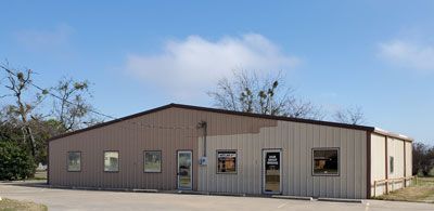 A large metal building with a lot of windows and a blue sky in the background.