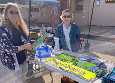 Two women are standing in front of a table with a sign that says `` i 'm a bad girl ''.