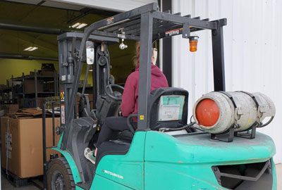 A woman is driving a forklift in a warehouse.