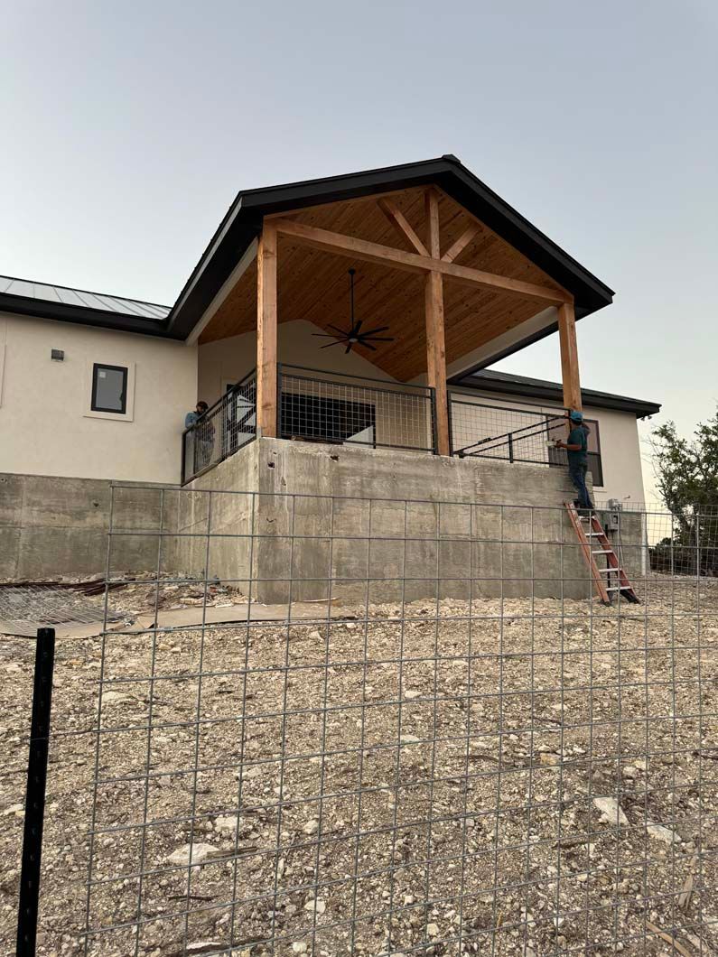 A man is standing on a ladder in front of a house under construction.