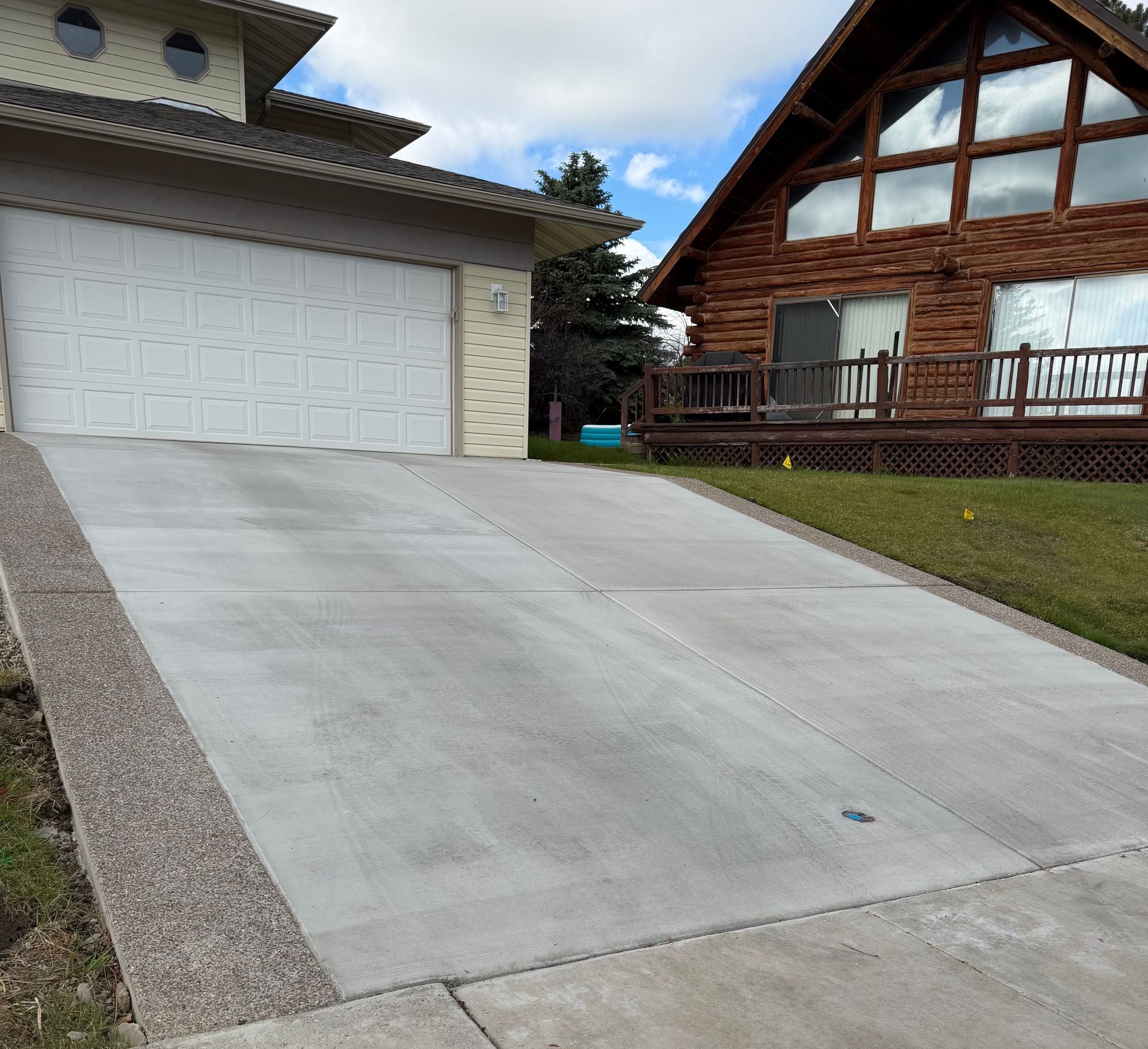 Concrete driveway beside a white garage and wood house with a front porch.